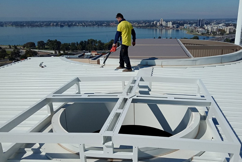 Man from a powdercoating services company cleaning a roof using a blower